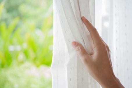 a hand pulling back a curtain.