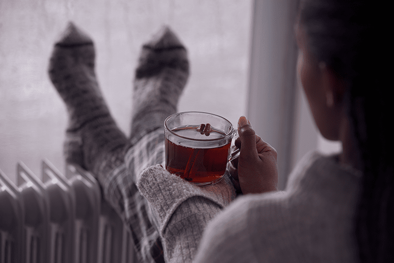 A person gets cozy on a chilly day. 6 Ways Your Furnace Keeps You Safe.
